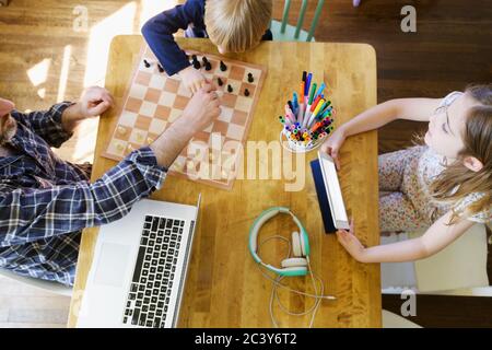 Vater, der von zu Hause aus arbeitet und mit Kindern spielt (5-6, 6-7) Stockfoto