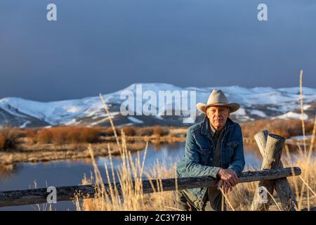 USA, Idaho, Sun Valley, älterer Mann im Cowboyhut, der sich gegen den Zaun lehnt Stockfoto