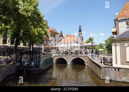 Alte Steinbrücke über Mient Kanal, mit Terrassen und viele Besucher und Touristen. Juni, Zentrum von Alkmaar, Niederlande. Stockfoto