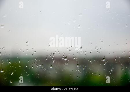 Regentropfen auf dem Glasfenster, die durch das Fenster schauen und dem Regen lauschen Stockfoto