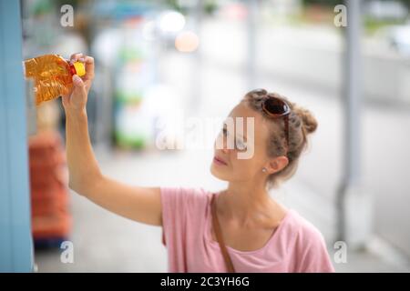 Abfall / Müll recycling Konzept. Junge Frau werfen eine Plastikflasche in eine dedizierte, Kunststoff Papierkorb. Mülltrennung Müll vor Drop Stockfoto