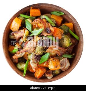 Gerösteter Butternusskürbis mit rosenkohl und Speck in Keramikplatte. Isoliert auf weißem Hintergrund. Stockfoto