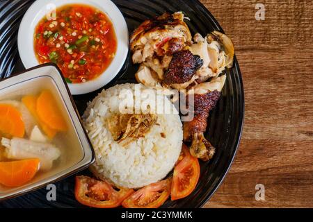 Hühnerreis mit gehacktem, geröstetem Huhn, serviert mit scharfem Chili-Sambal und Hühnersuppe. Mit Tomatenscheiben und gebratener Zwiebel auftoben. Stockfoto