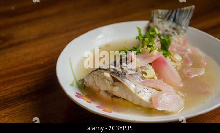 Gedünsteter Rohu-Fisch in Zitronensauce mit roter Zwiebel und garniert mit Koriander. Stockfoto