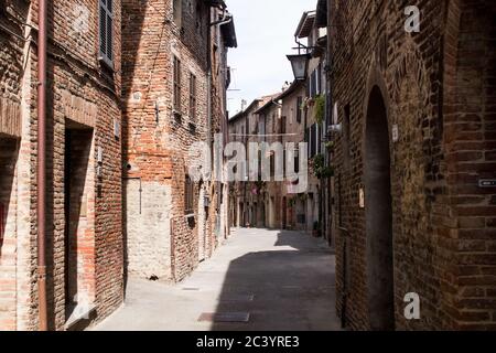 Gasse eines Dorfes von Umbrien, mit hölzernen Bogentüren an Fassaden von alten Ziegelhäusern Stockfoto