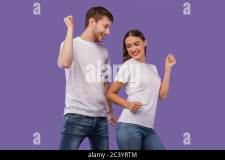Glückliche Partner tanzen auf pastellviolettem Studiohintergrund Stockfoto