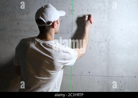 Der Meister macht Skizzen der Berechnungen auf der Betonwand Während der Bauarbeiten Stockfoto