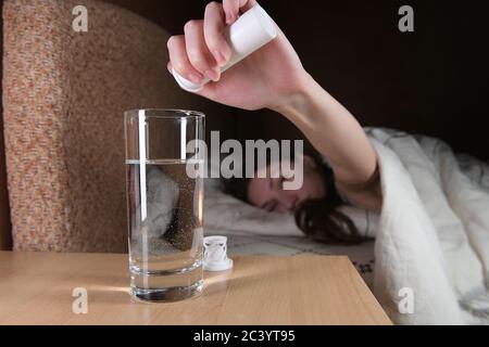 Frau legte eine lösliche Pille mit einem Medikament für Kater In einem Glas Wasser Stockfoto