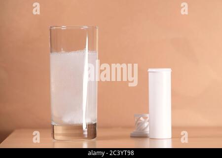 Auf dem Nachttisch befindet sich ein Glas, in dem eine Aspirin-Tablette aufgelöst wird. Stockfoto