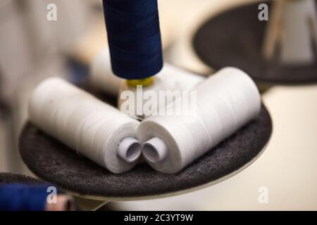 Baumwollgarnrollen für Nähmaschine. Blaue und weiße Garnrollen für die Bekleidungsindustrie Stockfoto