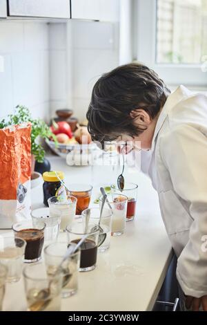 Ein junger Junge, der in der Küche zu Hause ist und wissenschaftliche Experimente macht, während er während der Covid-19-Pandemie unter Verschluss war. Stockfoto