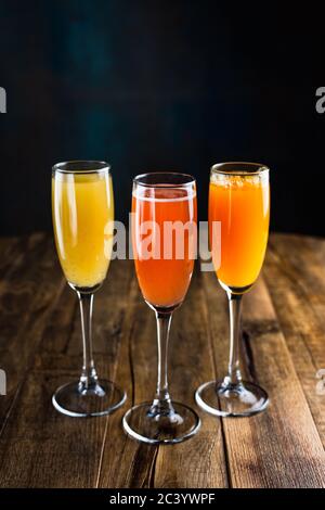 Drei verschiedene spritzige fruchtige Cocktails, rot, gelb und orange, in Flötengläsern Stockfoto