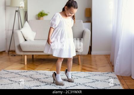 Kleines Mädchen trägt Mamas High Heels Schuhe spielen zu Hause Stockfoto