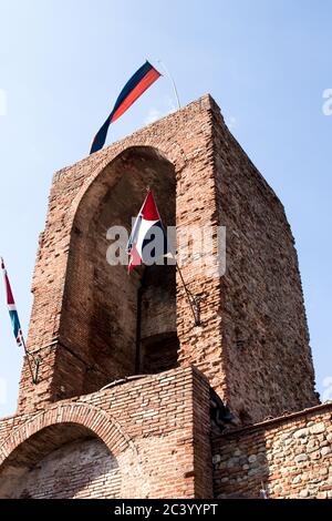 Glockentürme einer alten Stadt mit Fahnen rot und blau und blauen Himmel an der Spitze. Reisen Umbrien und Toskana, Italien Stockfoto