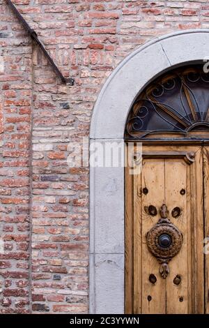 Detail eines Haupteingangs eines alten Hauses in einer antiken Stadt im Zentrum von italien. Die Tür ist dekoriert und die Wand um die Tür ist neu Stockfoto