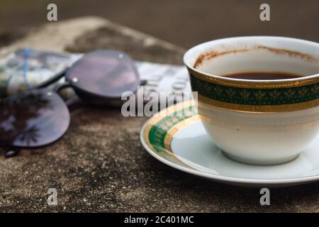 Tasse Kaffee, Gläser und Zeitung auf zementierter Oberfläche. Selektiver Fokus Stockfoto