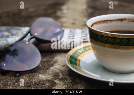 Tasse Kaffee, Gläser und Zeitung auf zementierter Oberfläche. Selektiver Fokus Stockfoto