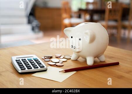 Economy-Konzept, Rechner mit Münzen, Bleistift und Sparschwein auf einem Tisch im Wohnzimmer, Finanzen berechnen und Haushaltsgeld sparen, Kopie s Stockfoto