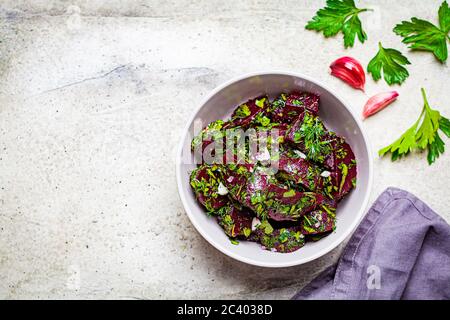 Rote Beete Salat mit Knoblauch und Kräutern in einer grauen Schüssel auf hellem Hintergrund. Stockfoto