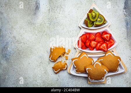 Weihnachts-Snacks - Lebkuchen, Kiwi und Erdbeeren auf einem Teller Weihnachtsbaum. Stockfoto