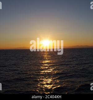 Sequenz von Bildern eines Sonnenuntergangs vom gleichen Standpunkt, Sequenz von Bildern des Sonnenuntergangs vom gleichen Standpunkt, Sonnenuntergang über dem Meer, Sonnenuntergang blauer Himmel über Dunkelheit Stockfoto