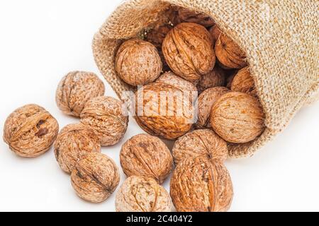 Extreme close-up von wallnuts aus einer Leinwand Sack hinter ihnen verschüttet. Auf weiß Isoliert Stockfoto