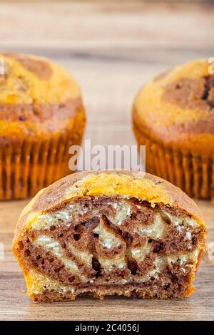 Nahaufnahme einer Hälfte gegessen Muffin mit einer kleinen Gruppe von Muffins hinter sich. Stockfoto