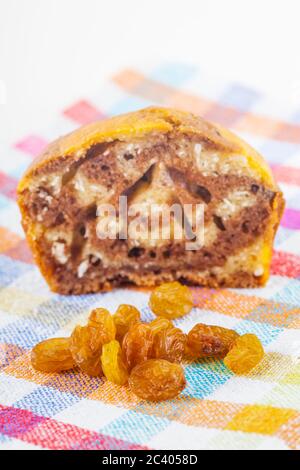 In der Nähe von Low Angle Shot eine Hälfte gegessen Muffin und eine große Gruppe von Rosinen auf einem Tuch Tuch mit einem weißen Hintergrund. Stockfoto