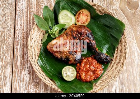 Gegrilltes Hähnchen mit Sambal Terasi und Scheiben von frischem Gemüse, frischen Tomaten, Gurken, Basilikumblättern Stockfoto