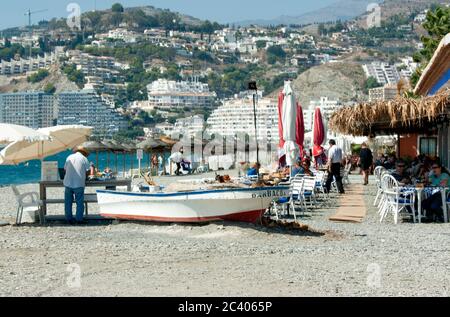 Ein Strandrestaurant an der Costa Del Sol. Frische Meeresfrüchte werden an einem sonnigen Sommertag über offenen Kohlen gegrillt. Stockfoto