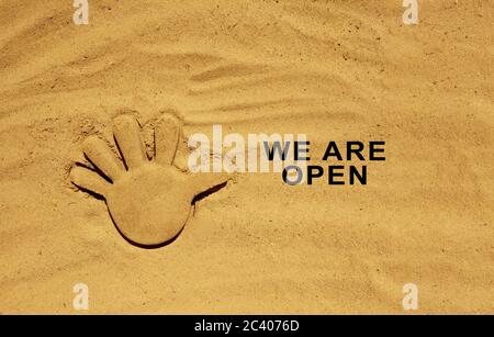 Ende der Quarantäne. Textnachricht W sind auf dem Sand offen. Willkommensschild am Strand. Hotel, Cafe, Strand, Travel Service Besitzer, der Gäste nach dem Kor begrüßt Stockfoto