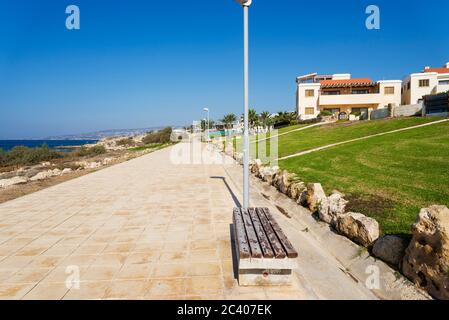 Bank an der Promenade entlang der Mittelmeerküste mit Hotels. Das Konzept der Reise und Erholung auf der Insel Zypern. Stockfoto