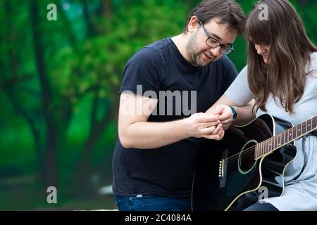 Bruder lehrt Schwester Gitarre in der Natur zu spielen Stockfoto