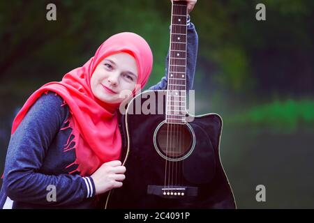 Portrait von blauäugigen muslimischen Mädchen mit Gitarre Stockfoto