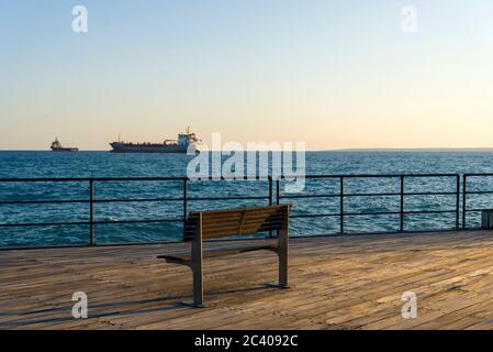 Bank auf Holzboden mit Blick auf das Meer. Blick von der Marina von Limassol Zypern. Stockfoto