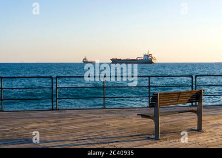 Bank auf Holzboden mit Blick auf das Meer. Blick von der Marina von Limassol Zypern. Stockfoto