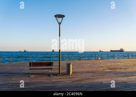 Bank auf Holzboden mit Blick auf das Meer. Blick von der Marina von Limassol Zypern. Stockfoto