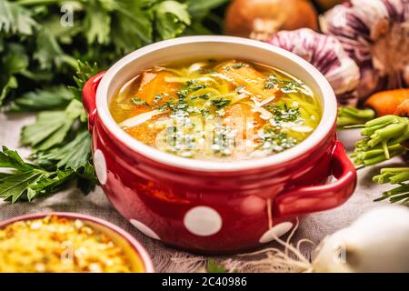 Hühnersuppe Brühe in einer Vintage-Schüssel mit hausgemachten Nudeln Karotte Zwiebel Sellerie Kräuter Knoblauch und frisches Gemüse Stockfoto