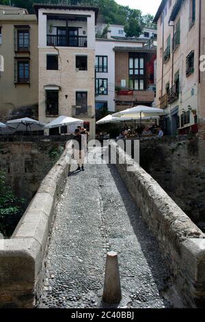 Wunderschöne, historische Granada Stadt Spanien. Blick entlang einer charmanten, alten, maurischen Fußgängerbrücke die Puente Espinosa, in der Altstadt zu Cafés und Restaurants. Stockfoto