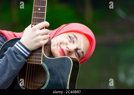 Portrait von blauäugigen muslimischen Mädchen mit Gitarre Stockfoto