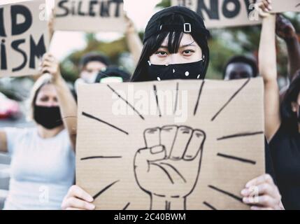 Asiatische Mädchen tragen Gesichtsmaske während Protest gegen Rassismus auf der Straße der Stadt - Gleichberechtigung und Demenstration Konzept - Fokus auf Augen Stockfoto