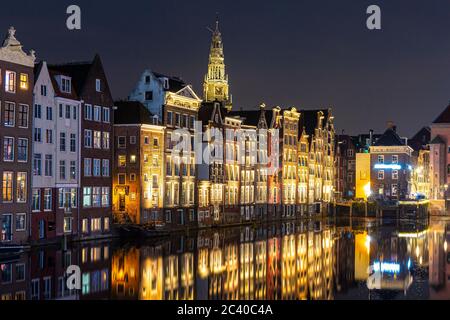Amsterdam Damrak traditionelle holländische Architektur bei Nacht. Tour Kreuzfahrtschiffe im Vordergrund. Stockfoto