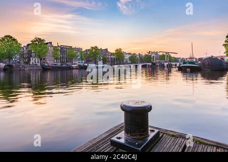 Amsterdamer Straßen und Kanäle in der Dämmerung. Brücken beleuchtet, Sommersaison. Beliebtes Reiseziel für Touristen. Stockfoto
