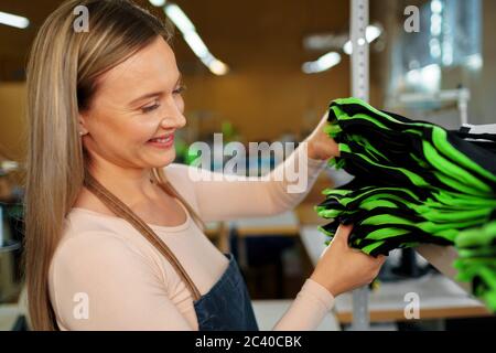 Nette Frau Schneider hält gerade genäht T-Shirt Stockfoto