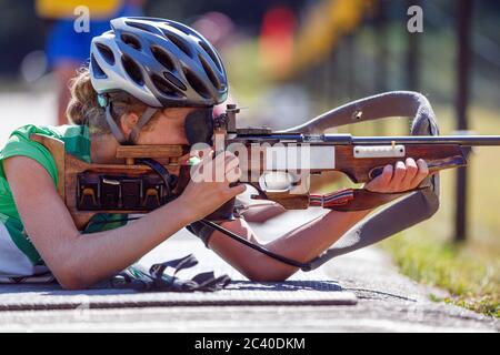 Junges Mädchen mit dem Ziel ihr Gewehr auf Biathlon Schießstand. Sommer Biathlon Wettbewerb Bild mit unkenntlichen Athleten Stockfoto