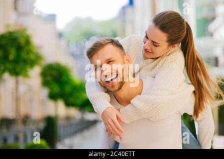 Junge Frau hinter mans Rücken umarmt hinter seinem Hals Stockfoto