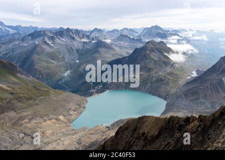 Sicht vom Bättelmatthorn auf der Grenze Italien-Wallis hinunder zum Griessee mit der Windenergieanlage und zur Passhöhe des Nufenenpasses mit der Pass Stockfoto