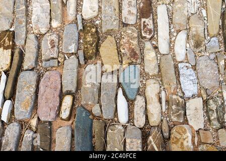 Mehrfarbige Steine auf dem Boden. Verschiedene Formen und Größen. Textur der Steinbeschichtung. Stockfoto