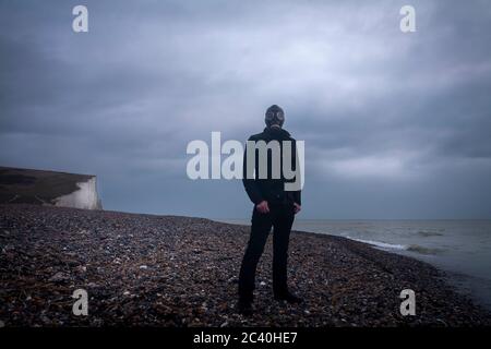 Mann in Gasmaske am Strand Stockfoto