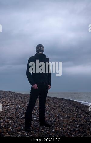 Mann in Gasmaske am Strand Stockfoto